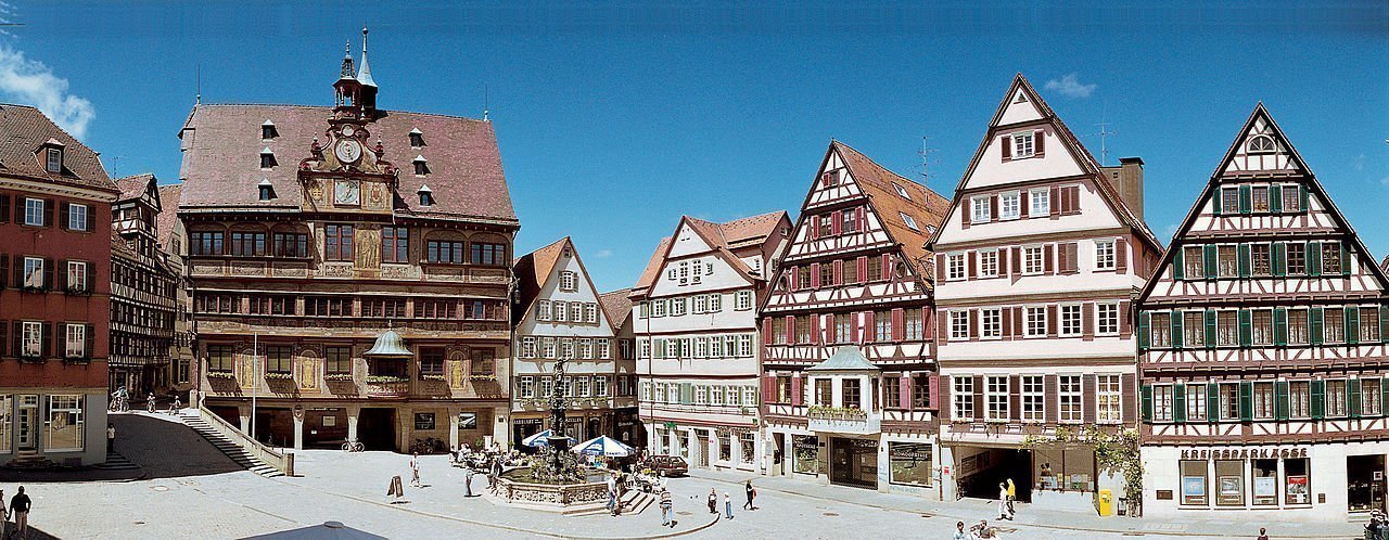 Historische Fachwerkhäuser und Rathaus am Tübinger Marktplatz unter blauem Himmel